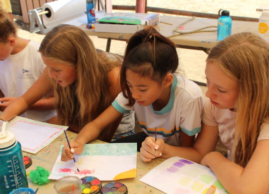 girls learning to paint in class