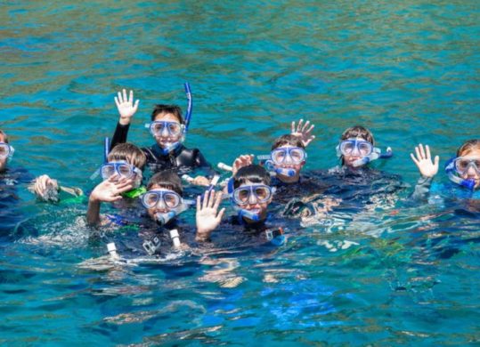 snorkelers in ocean waving at camera