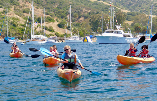 campers on kayaks being lead out of the bay by a counselor