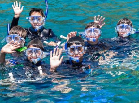 boys waving in water in snorkel gear