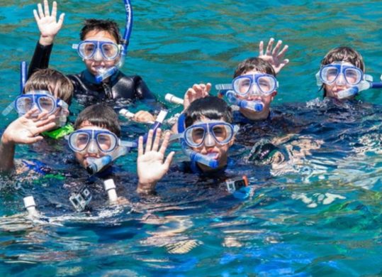 boys waving in water in snorkel gear