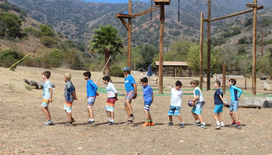boys in a line with their hands behind their back in a challenge activity