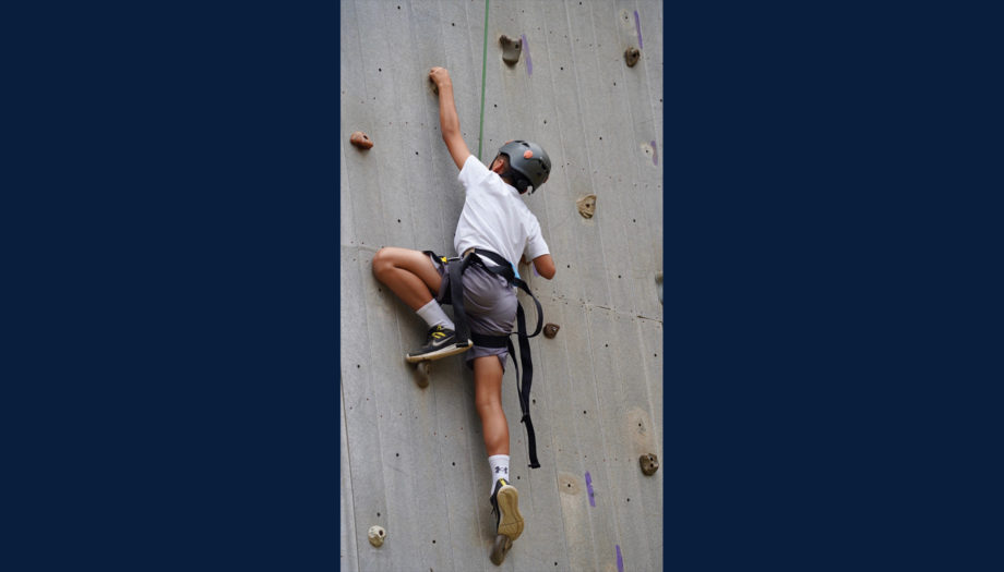 camper on the climbing wall in protective gear and harness