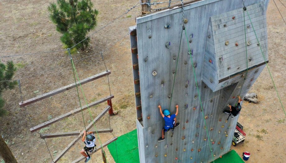 campers climbing the large wooden climbing wall