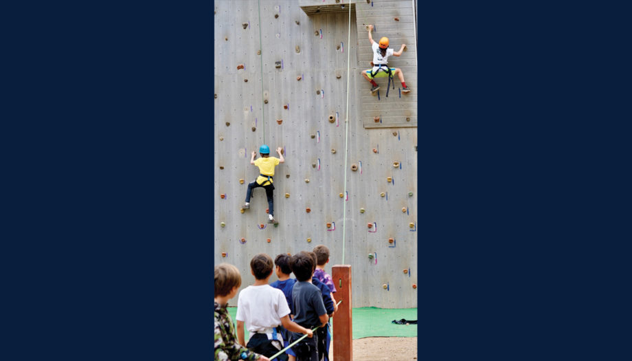 campers on the climbing wall while other campers look on