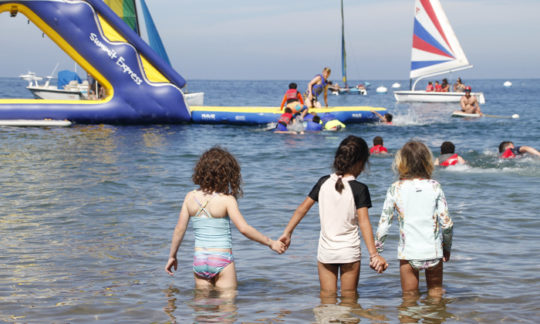three young girls holding hands in the shallow water