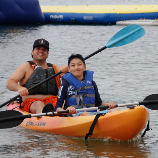camper and counselor kayaking together through the harbor