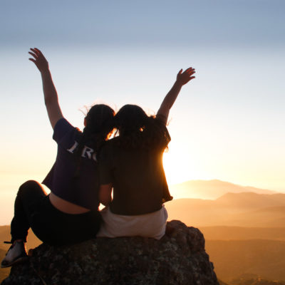 campers with their hands in the air at sunset