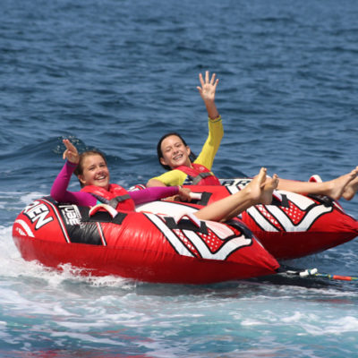 Two campers being pulled in a tube by a powerboat