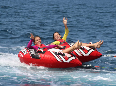 Two campers being pulled in a tube by a powerboat