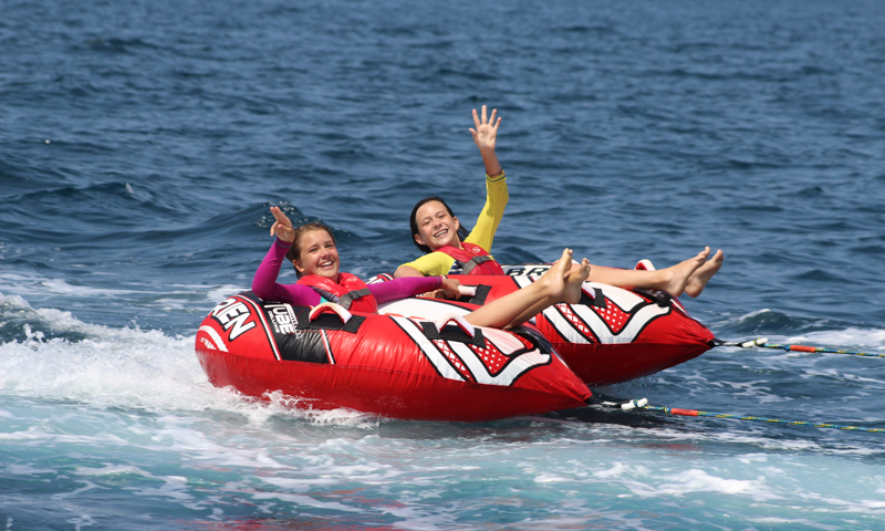 Two campers being pulled in a tube by a powerboat