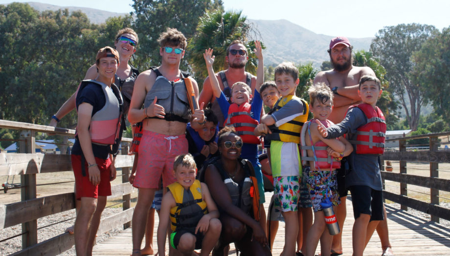 staff and campers posing on the dock while wearing life jackets