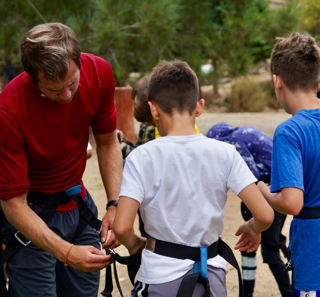 instructor adjusting a camper's safety equipment