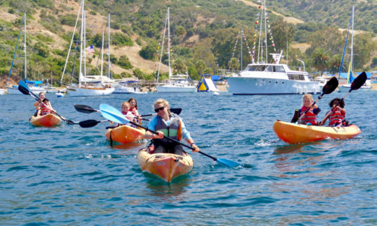 campers on kayaks being lead out of the bay by a counselor