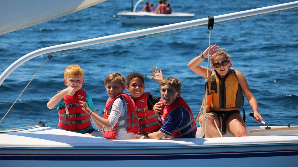 summer campers smiling and waving while on boat in catalina