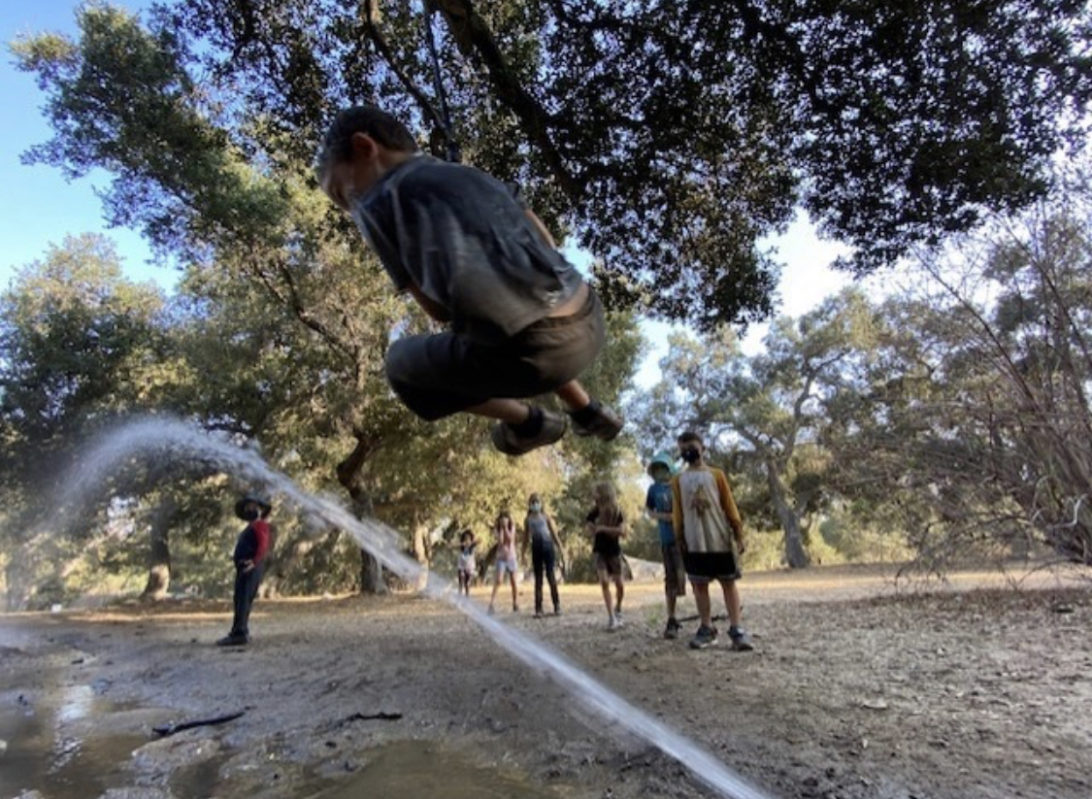 boy jumping over hose