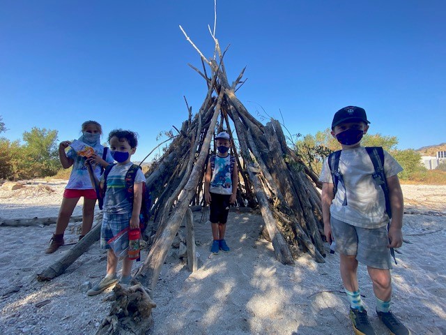 kids posing in front of a stick fort